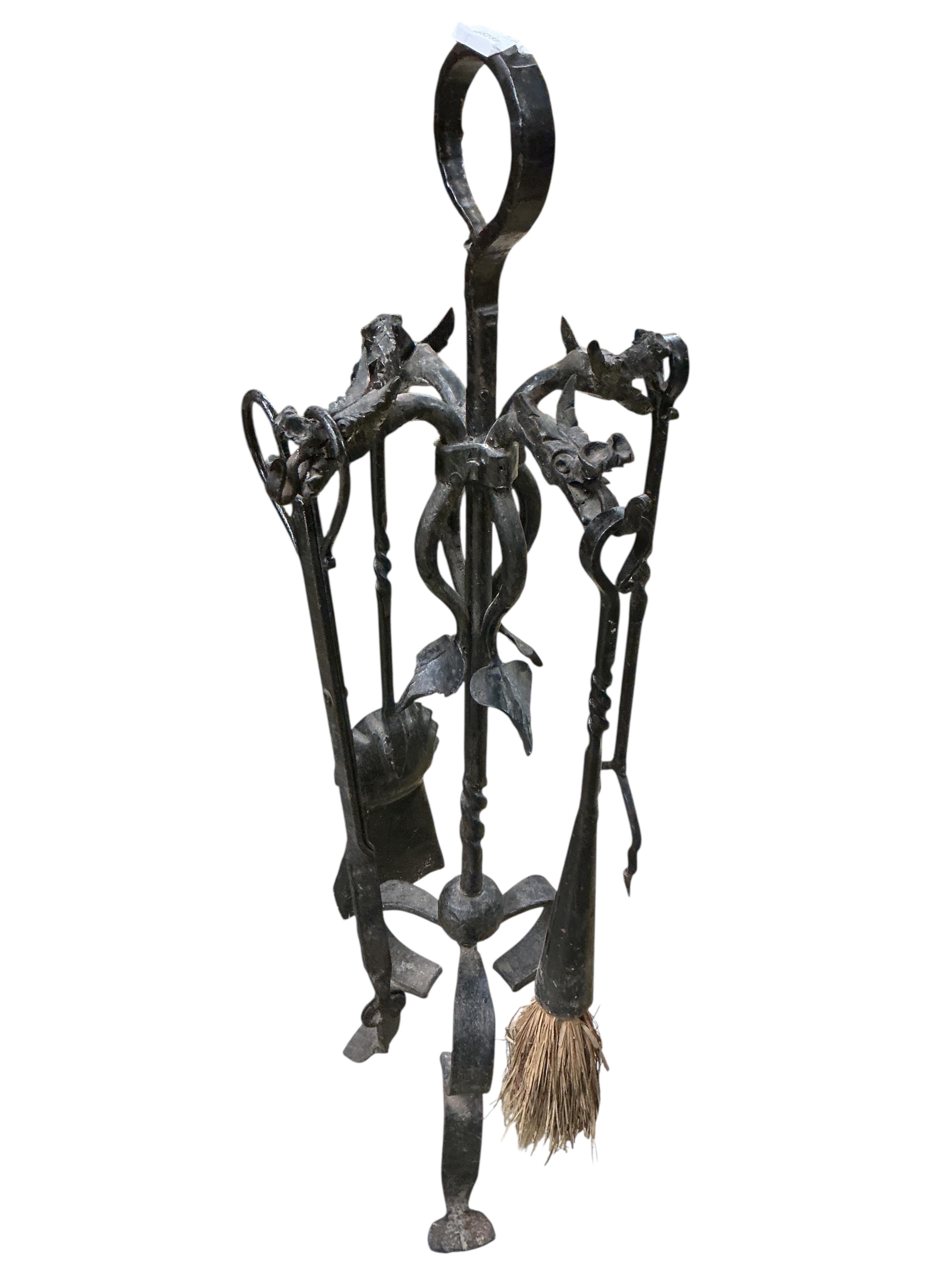 A set of wrought iron fire implements on dragon head stand